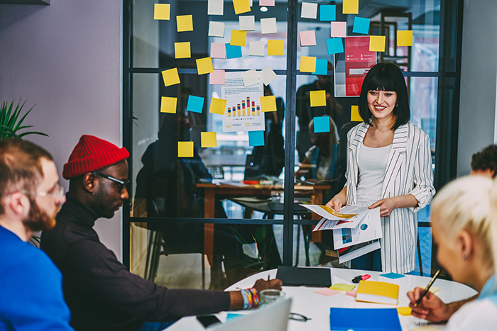 Office meeting planning the next task, content includes post it notes and graphs.